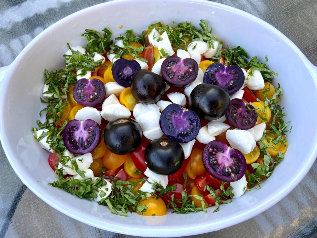 caprese salad in a bowl made with halved yellow, red and purple-fleshed cherry tomatoes
