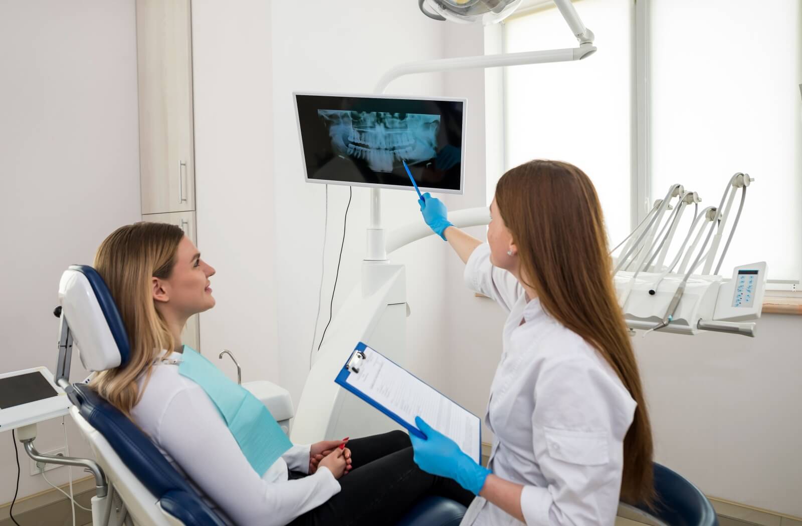 A dentist shows their patient an X-ray of their teeth