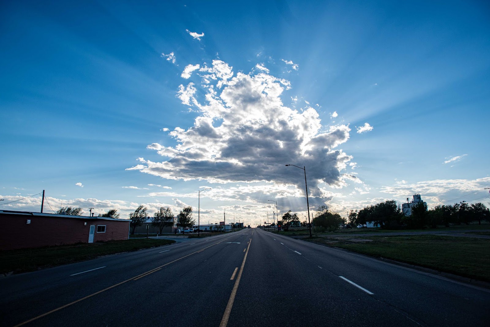 Photo of a highway underneath a blue sky and fluffy clouds 