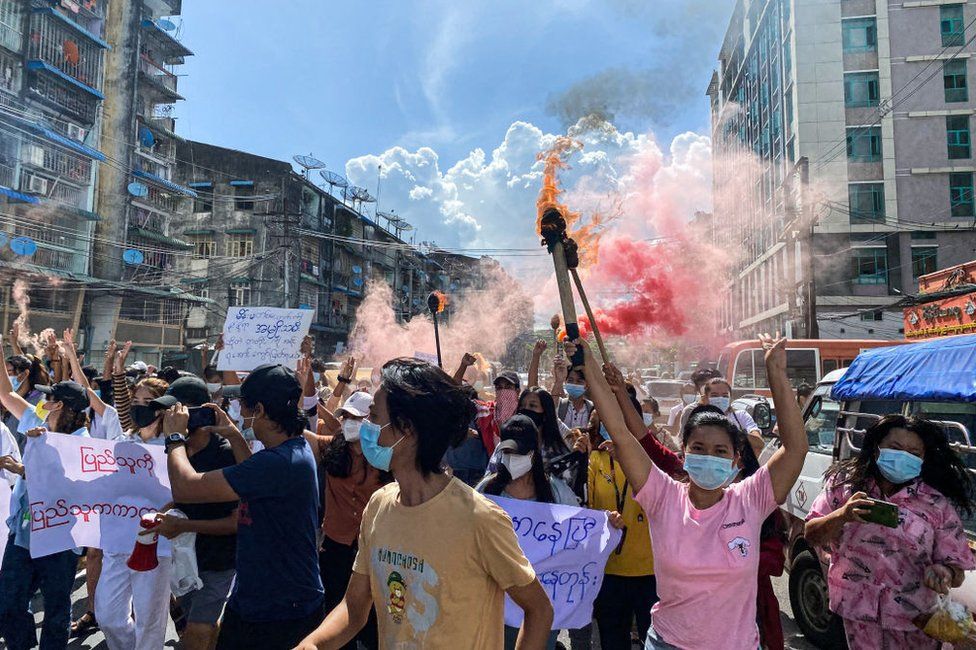 Women holding banners, emergency flare sticks and fire sticks as they march during a demonstration against the military coup in Yangon on July 14, 2021.