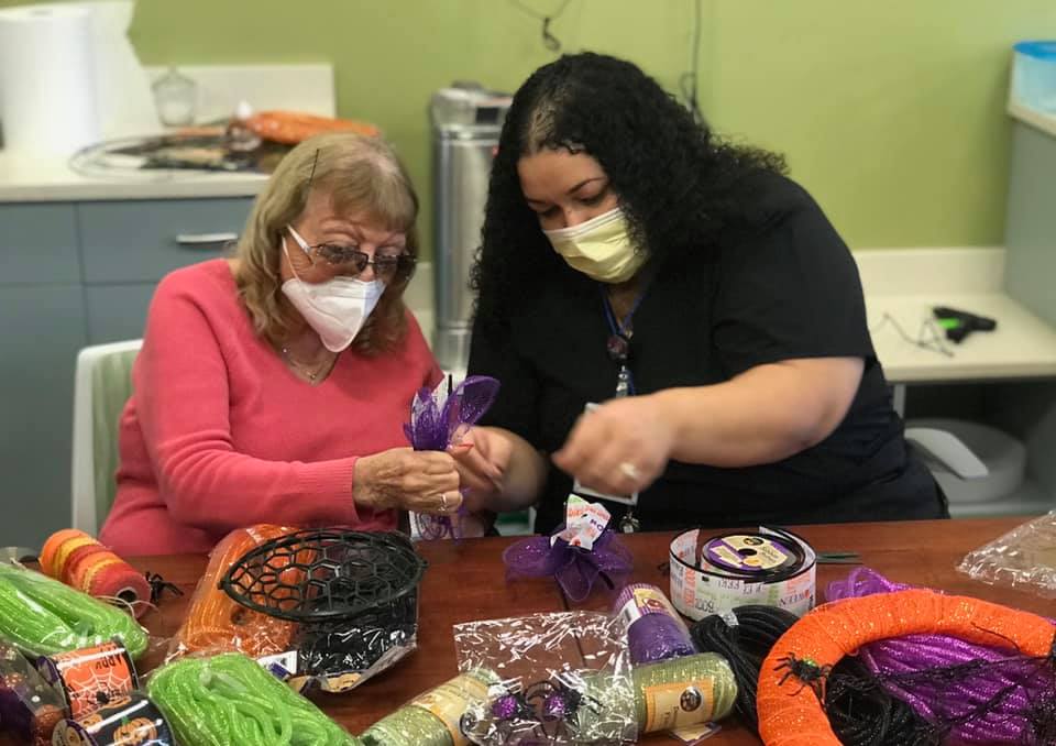 A senior citizen receiving a level of care in an assisted living facility from a staff member