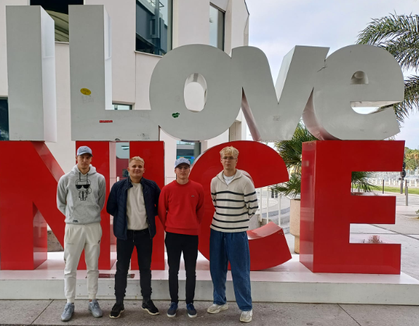 A group of men standing in front of a large sign

Description automatically generated