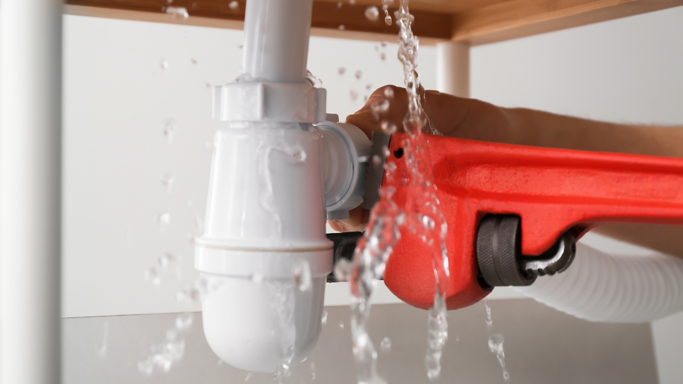 Plumber fixing leaking water pipe