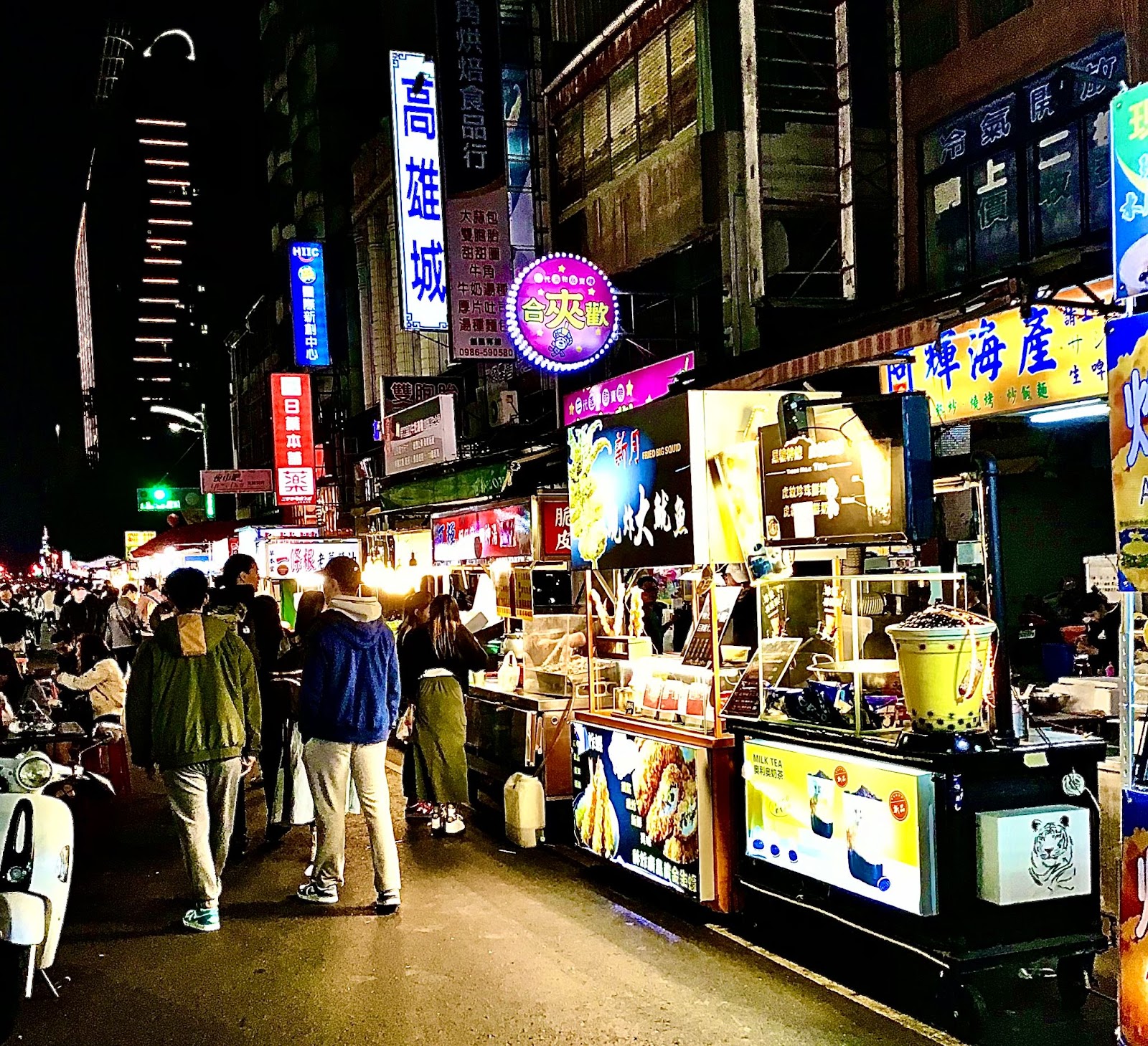 photo of Taiwan night market with citizens and tourists walking by motorbikes and pedestrians as well as snack stands and shops