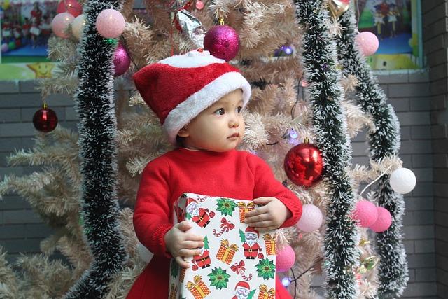 クリスマスの装飾を背景に、プレゼントを持った幼児の写真