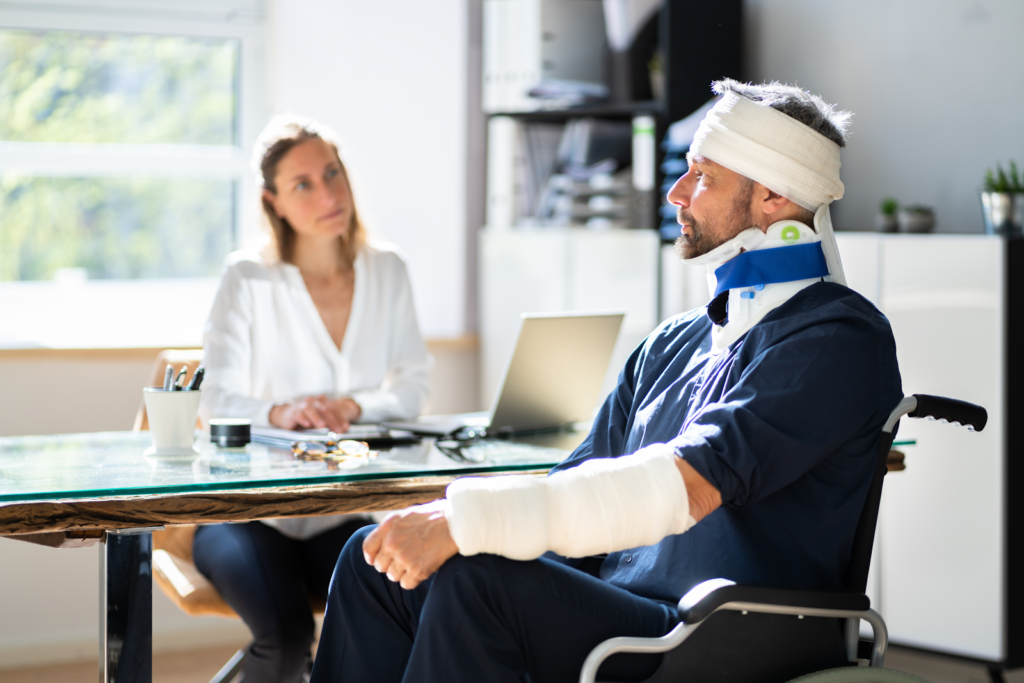 man in bandages and wheelchair talking to a personal injury lawyer in carmel