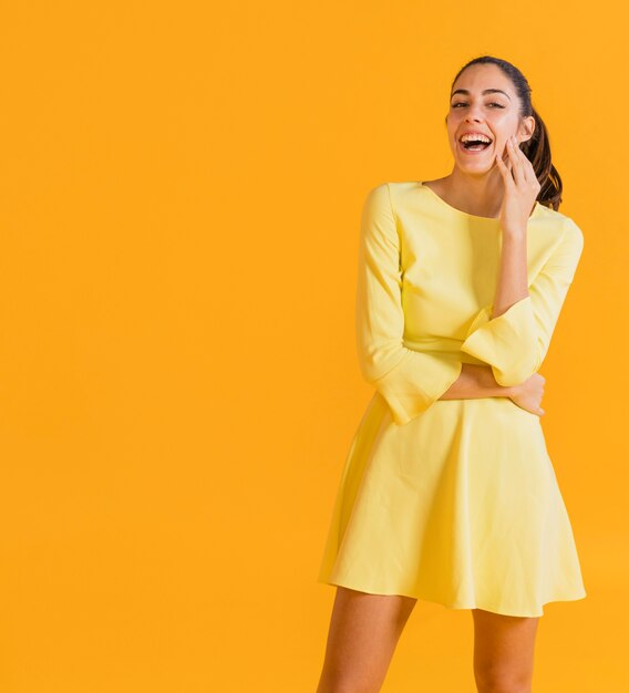 A woman wearing a yellow dress and laughing.