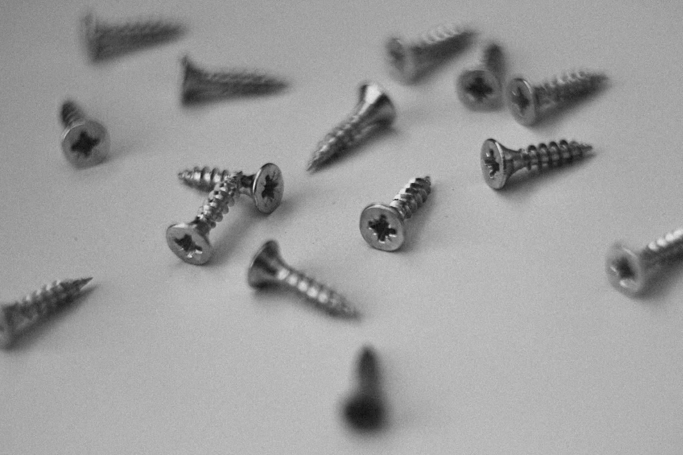 A group of screws on a white surface
Description automatically generated
