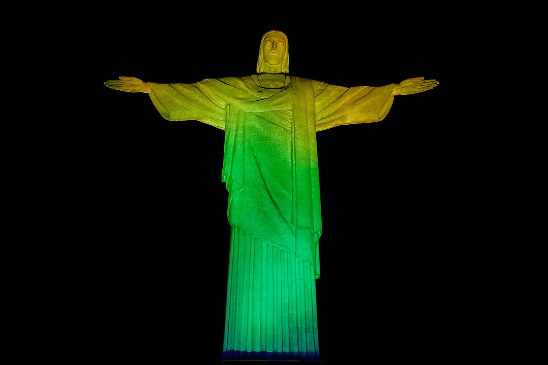 The statue lit in the colors of the Flag of Brazil
