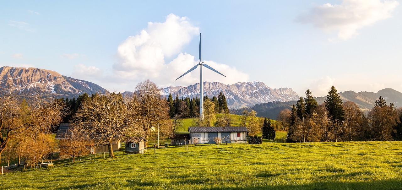 A serene landscape with a wind turbine in the foreground, symbolizing renewable energy production forecast, set against a backdrop of lush greenery and distant mountains.