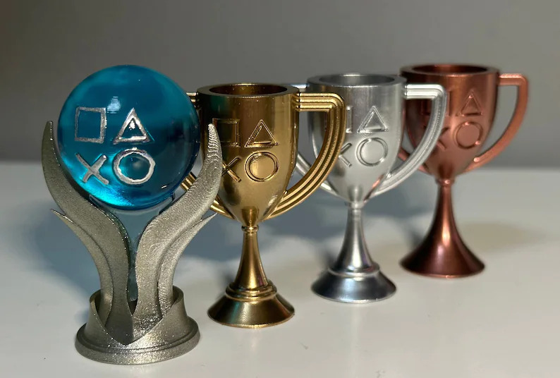 A promotional image of the mini 3D resin printed and hand painted PlayStation 5 trophy decorations from 3dimpressionsUK on Etsy. 