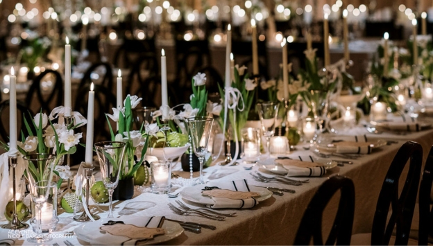 A beautifully set table with luxurious linens and green plant centerpieces 