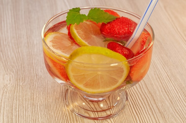 A glass of water with lemon slices and strawberries