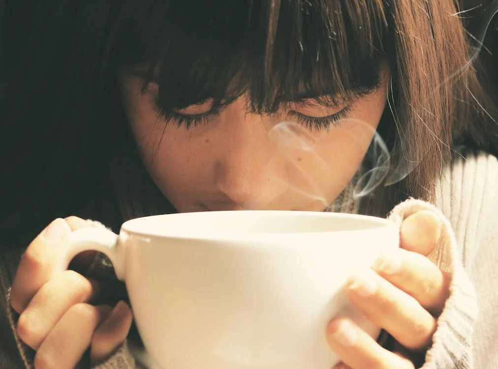 Woman drinking tea from a large teacup while practicing tea mindfulness