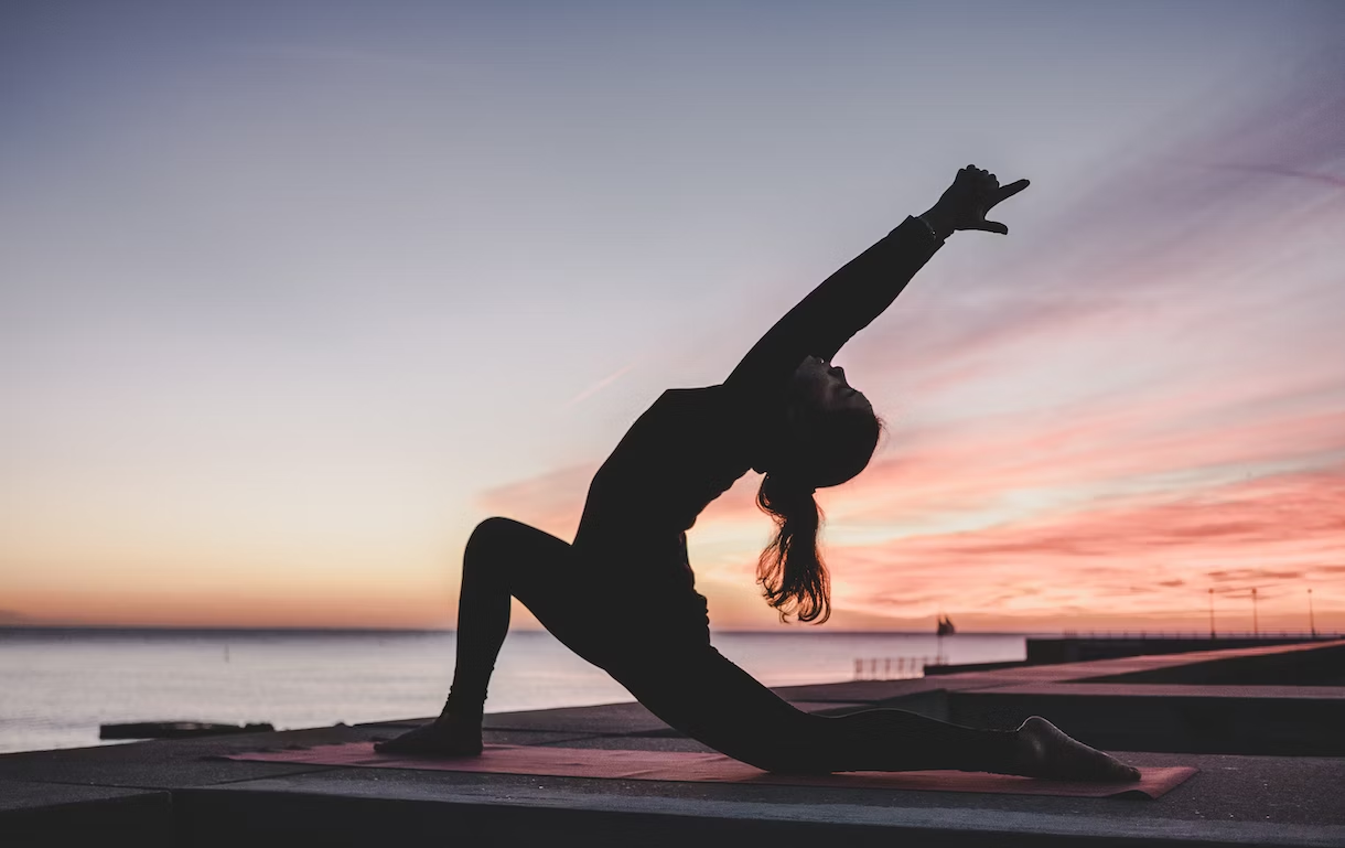 a woman practicing yoga in the sunset