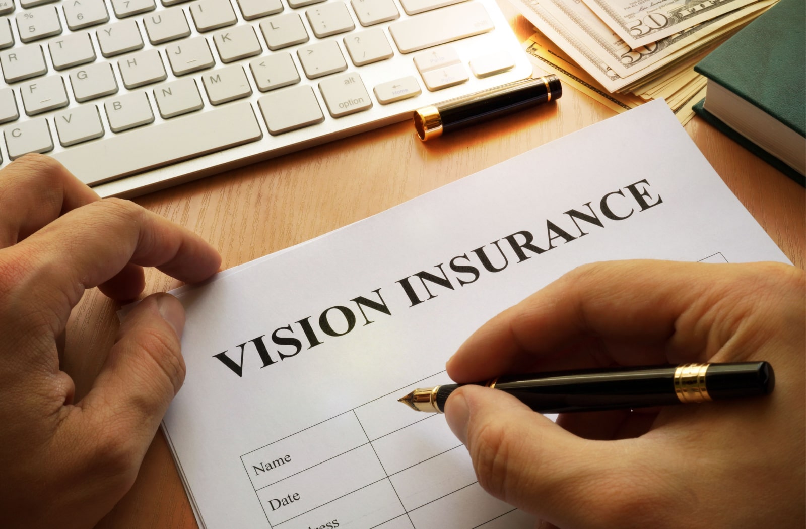 A person filling out a vision insurance application with a pen