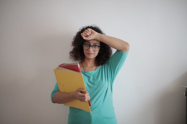 A person holding a yellow folder with documents, raising her arm over her head.