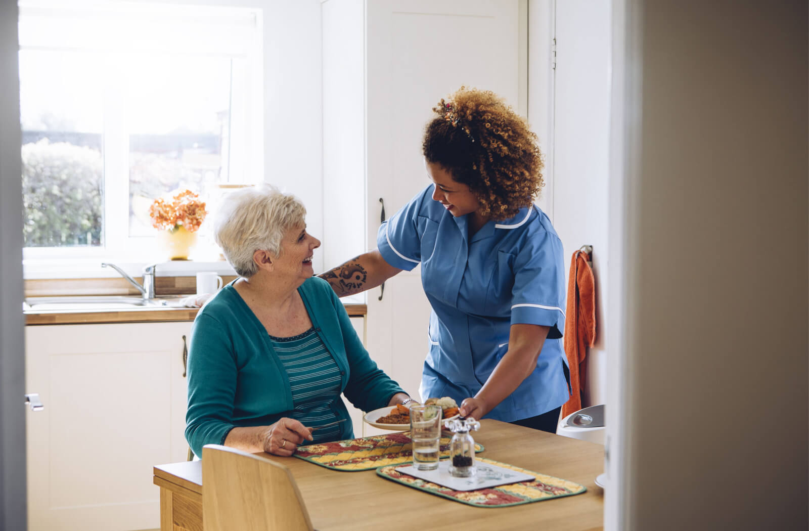 A personal care home staff serving a healthy meal to a resident.