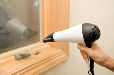 how to insulate your windows in cold weather homeowner using hairdryer applying window insulation kit custom built michigan
