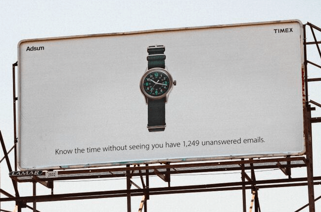 Times billboard ad. There's a picture of a watch against a blank background. Underneath, the text reads: “Know the time without seeing you have 1,249 unanswered emails.”
