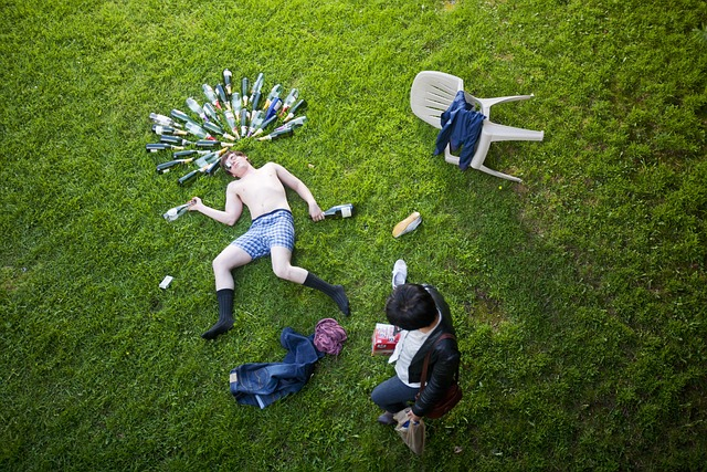 A student is passed out on the quad from drinking, with bottles arrayed around him