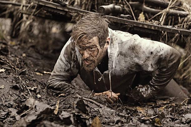 Caucasian blonde handsome man crawling under obstacle during mud run Caucasian blonde handsome man crawling under obstacle during mud run survival training stock pictures, royalty-free photos & images