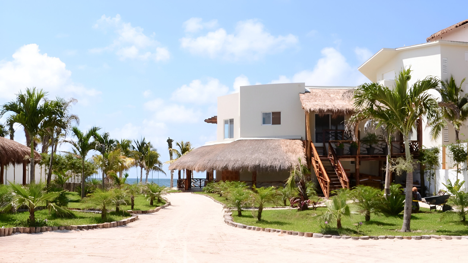 A secluded vacation rental in Cancun with thatched roofs and palm trees overlooking the ocean