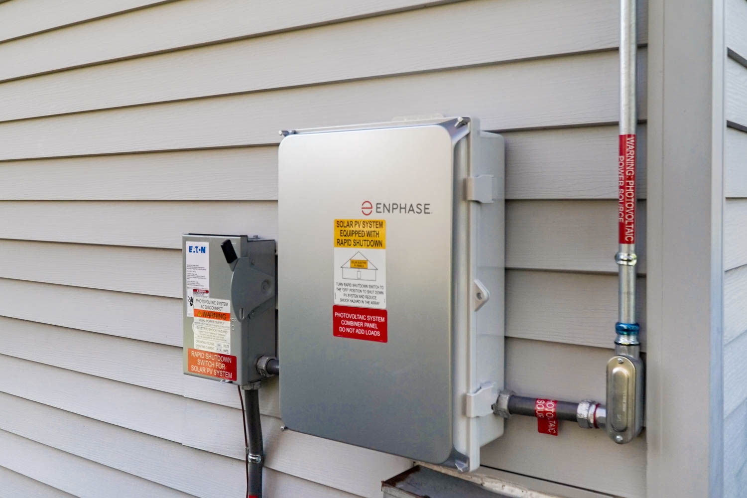 Enphase electrical box for home solar system with red and white warning sign. 
