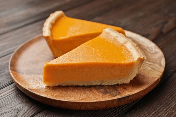 Slices of pumpkin pie served on a wooden plate