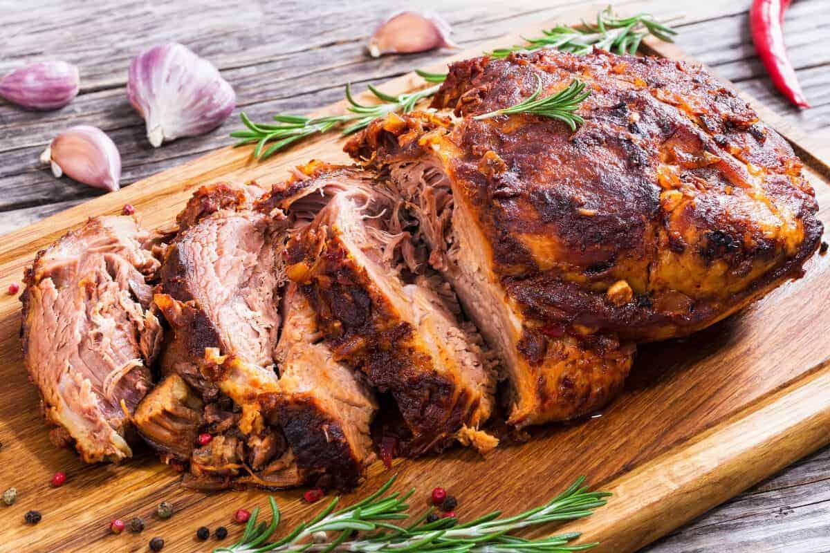 Un umăr de porc afumat și feliat pe o masă de tocat