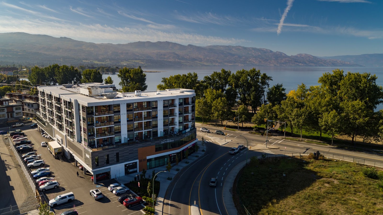 an exterior view of The Shore Kelowna, an apartment-hotel building, overlooking Okanagan Lake on a sunny day in Kelowna's lower mission neighbourhood