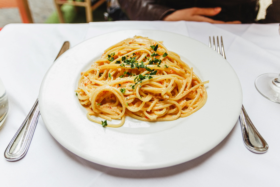 A plate of pasta with sauce and parsley on it

Description automatically generated