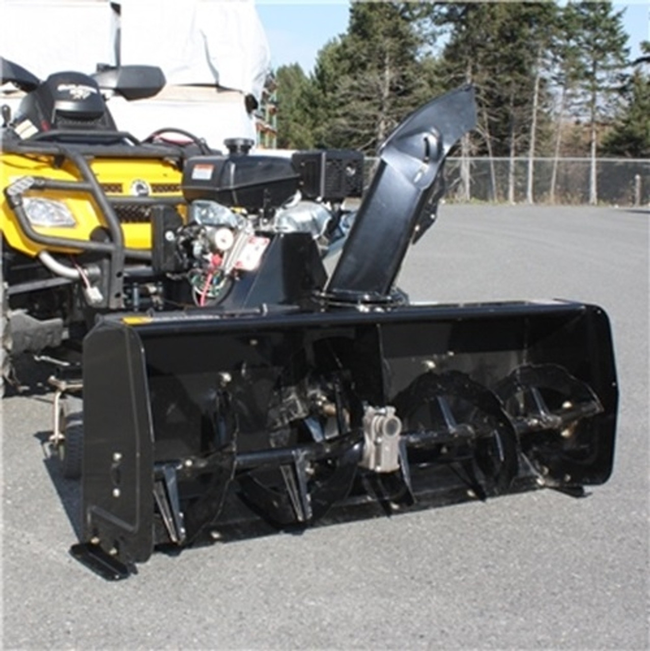 A front-facing image of a Can-Am Maverick X3 Snowblower by Bercomac, installed on the front end of an ATV and parked in a concrete lot.