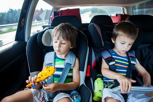 Two Boy In Car Seats Traveling In Car And Playing Stock Photo - Download  Image Now - Car, Child, Toy - iStock