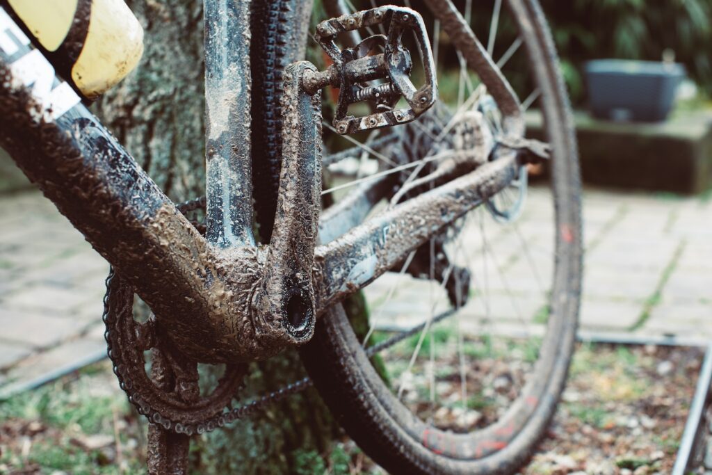 a dirty bike parked next to a tree