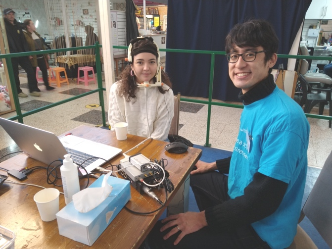 A person and person sitting at a table with a computer

Description automatically generated