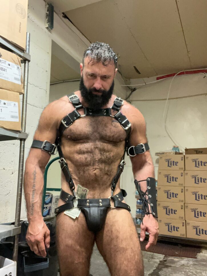 gay greek male covered in leather BDSM body harnesses comes back from gogo performing on stage with five dollar bills shorved in his leather studded jockstrap