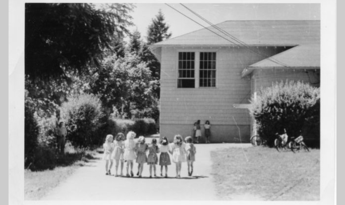 A group of children standing in front of a house

Description automatically generated