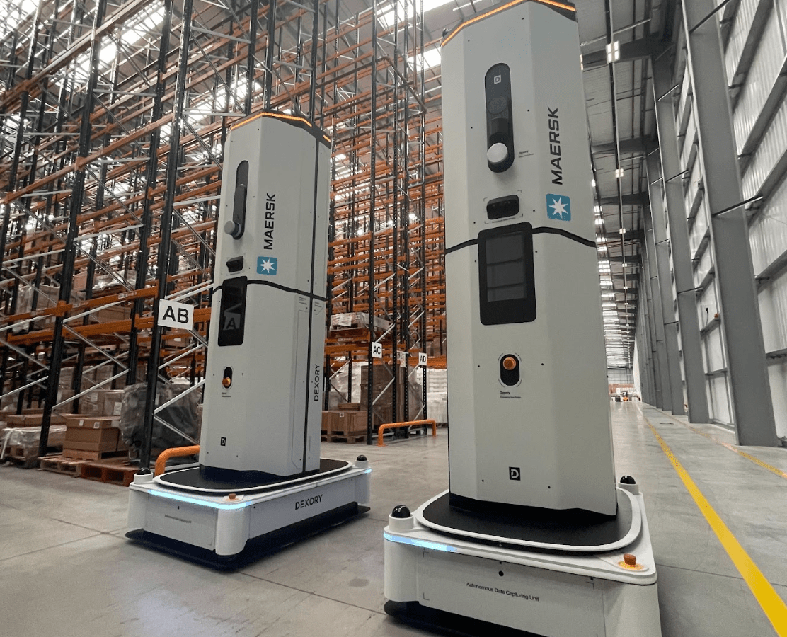 Perspective view of two grey Dexory robots side by side in a Maersk factory