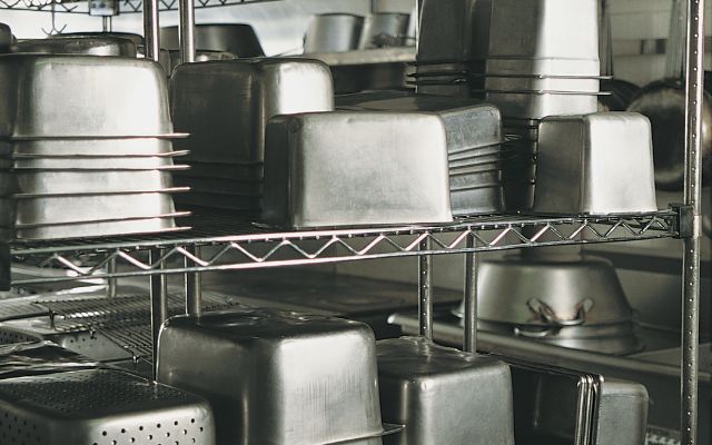 Stack of commercial kitchen equipment supplies in a stainless steel storage.