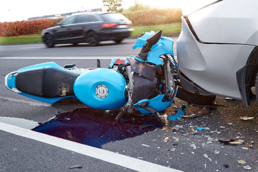A damaged motorcycle and a car, on an asphalt road immediately after the accident in spring hill