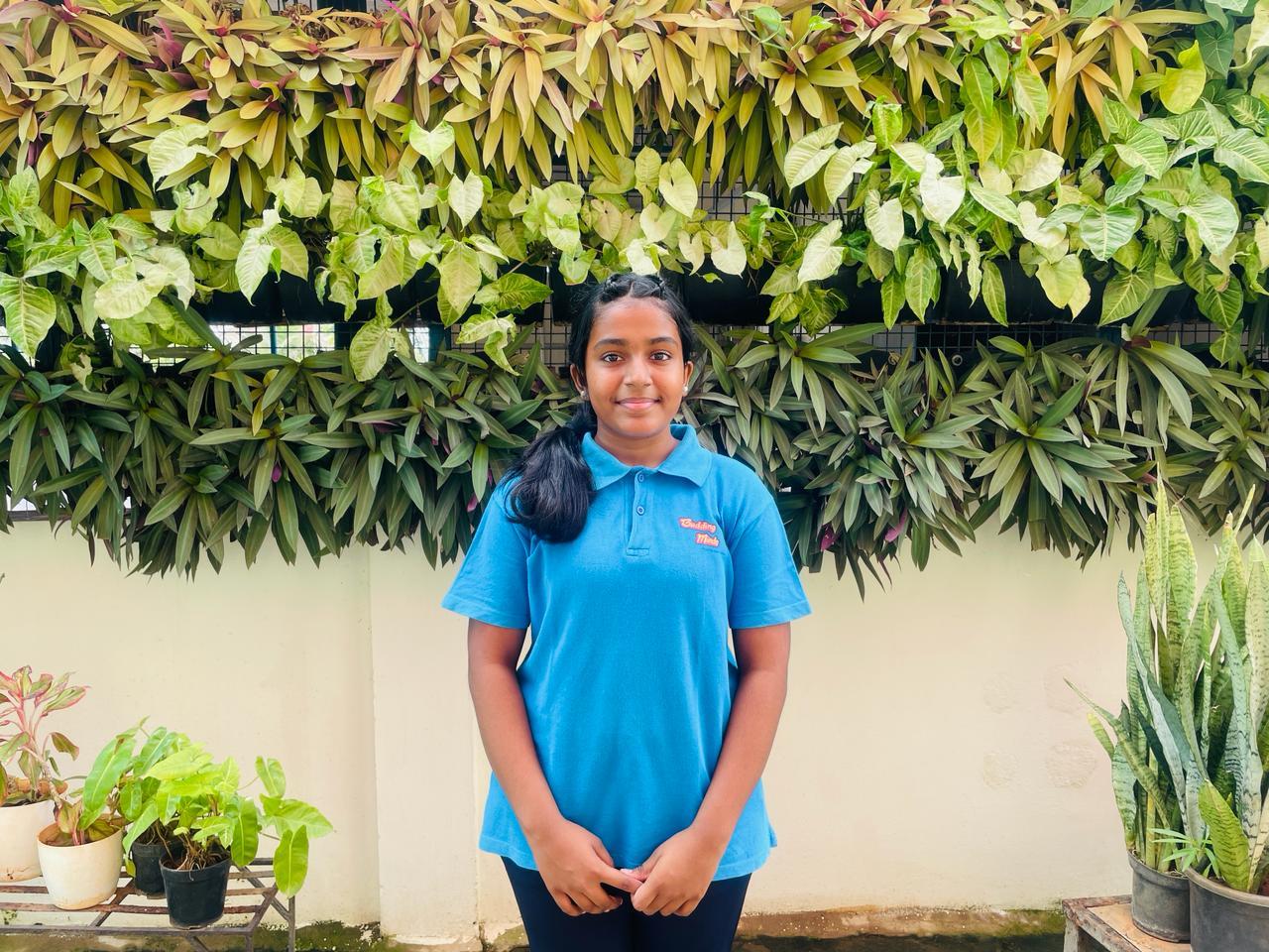 A child standing in front of a wall of plants

Description automatically generated