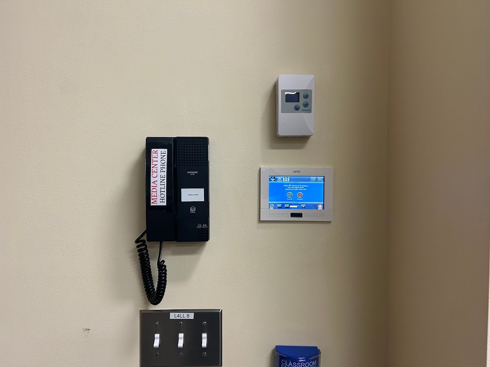 View of wall in the front of the room: Hotline phone, touch control panel