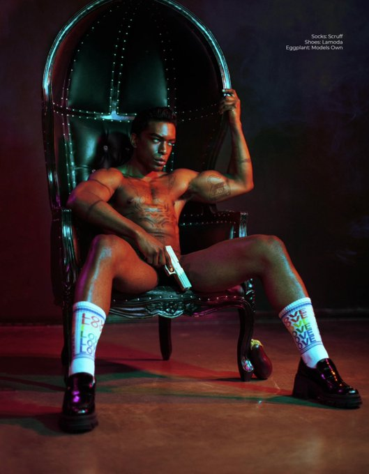 Jordan Jameson sitting in a studded leather chair wearing love athletic socks naked holding a silver gun over his crotch