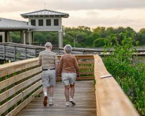 Senior couple holding hands and walking across a bridge after moving to Delray Beach FL