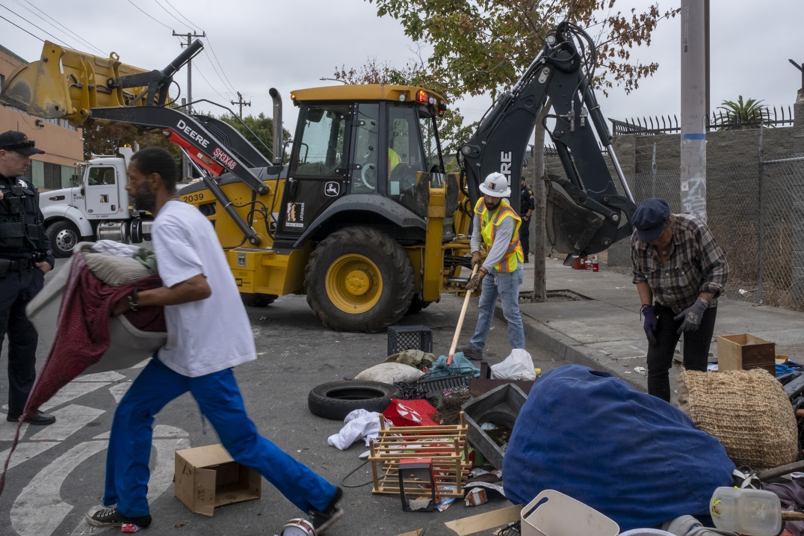 Galtney rushes to retrieve items from a pile being swept by assistant to the city manager, Peter Radu, October 4, 2022. (Yesica Prado, SF Public Press)
