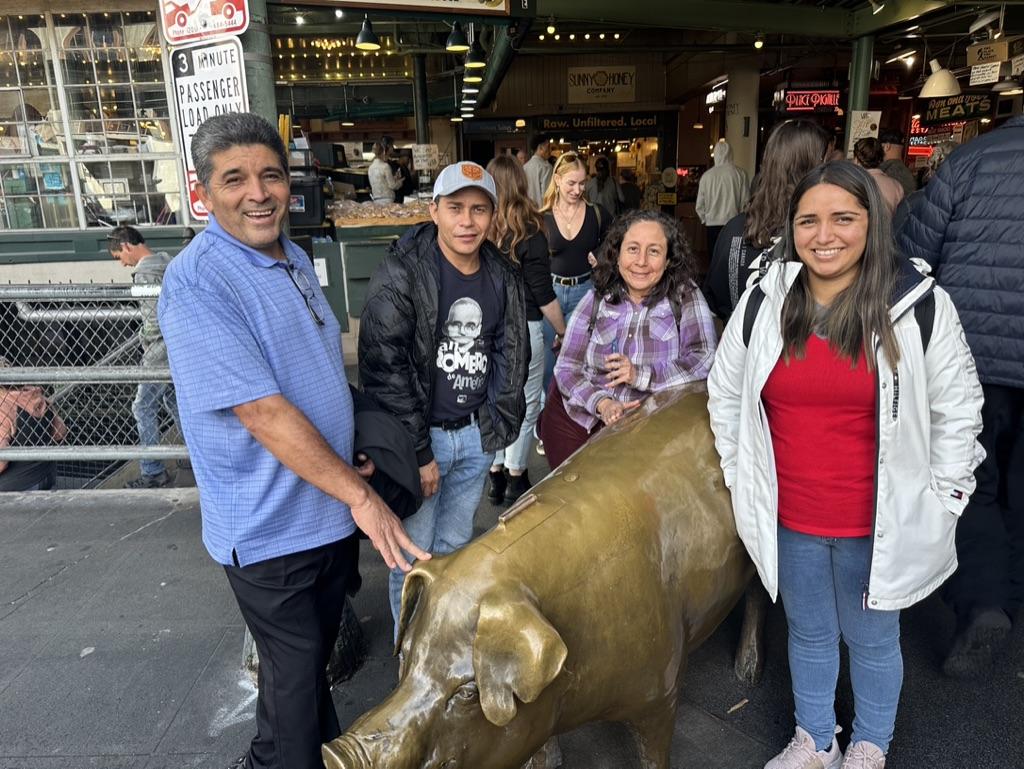 A group of people posing with a statue of a pig

Description automatically generated