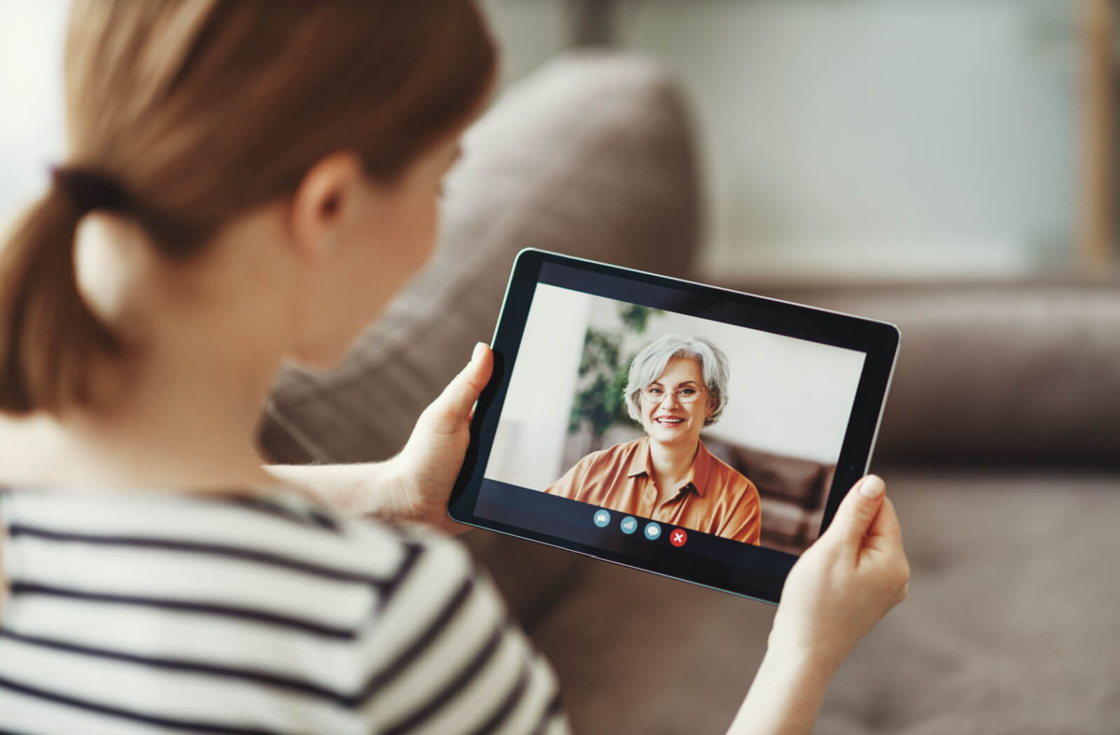 A woman talking to her senior mother in an assisted living community over a video call using a tablet