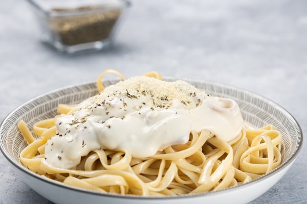 A bowl of pasta with creamy sauce on top