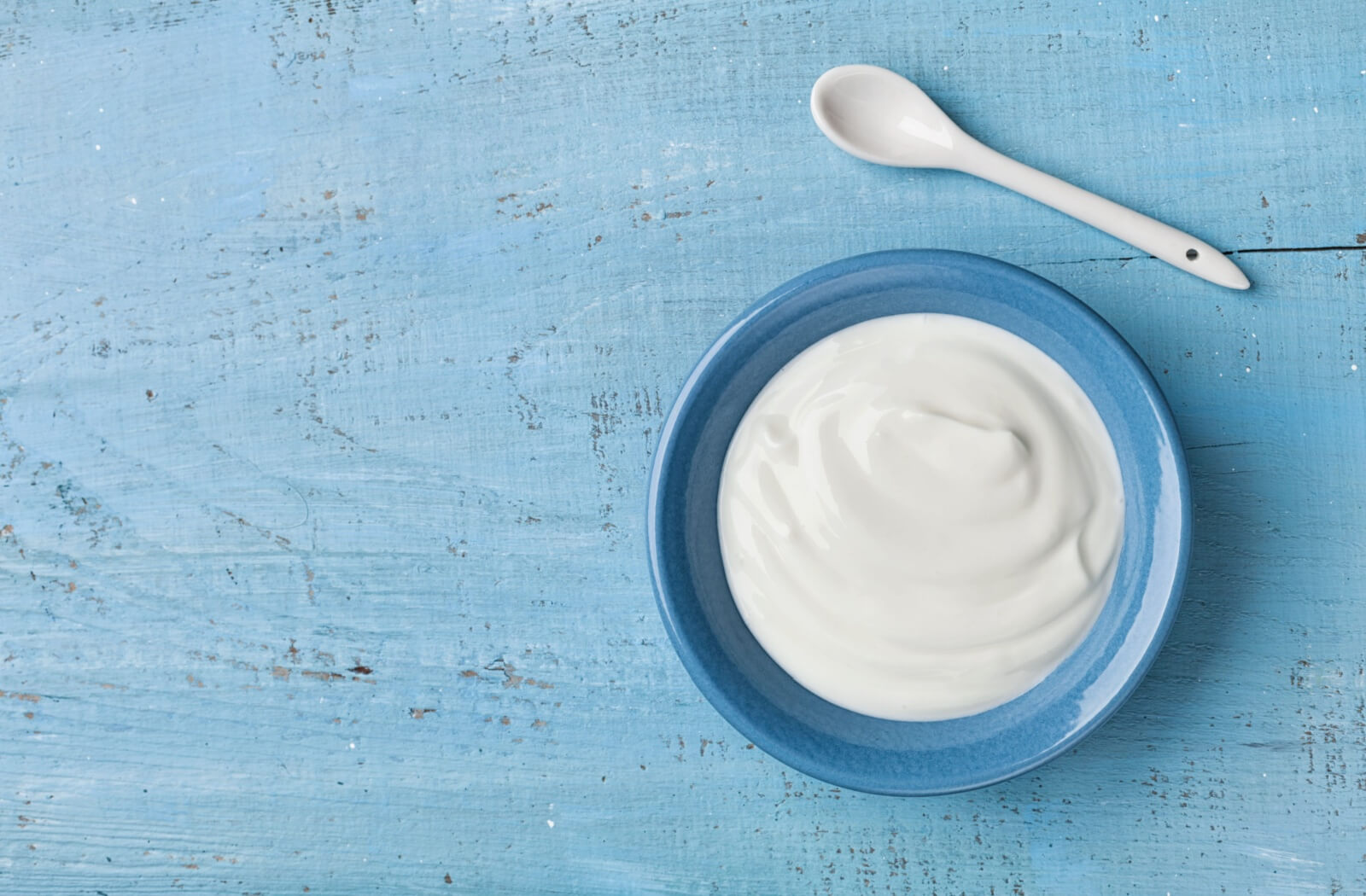 A bowl of yogurt on a blue wooden table.
